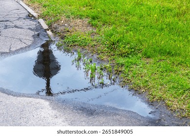 There is a small puddle of water located on the side of a road