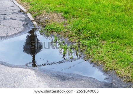 There is a small puddle of water located on the side of a road