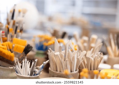 There are stands with pottery tools on table - sets of brushes, spatulas, hinges - close-up. Sets of tools for coloring and final processing of ceramic products. - Powered by Shutterstock