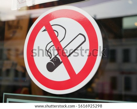 There is a sticker on the glass, smoking is prohibited. Public place without cigarettes. No smoking sign sticker on glass with out of focus public institution