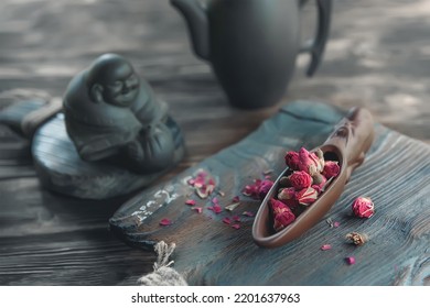 there is a teaspoon of rosebud tea on the wooden table. Tea time, cozy atmosphere. Kitchen still life in Chinese style with pink floral tea on a background of contrasting morning light.