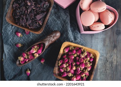 there is a teaspoon of rosebud tea on the wooden table. Tea time, cozy atmosphere. Kitchen still life in Chinese style with pink floral tea on a background of contrasting morning light. Top view.
