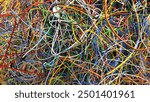 there are a lot of thin wires lying, tangled colored wires, scraps of copper wires lying entangled with each other, colored cobwebs lying in the garage after the work of an auto electrician