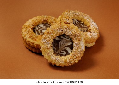 There Are Three Round Shortbread Cookies With Chocolate Filling On A Brown Background