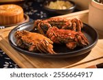 There are three steamed hairy crabs in a plate with moon cake and steamer next to them