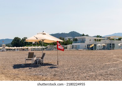 There is an umbrella on the beach and the flag next to it says game over.