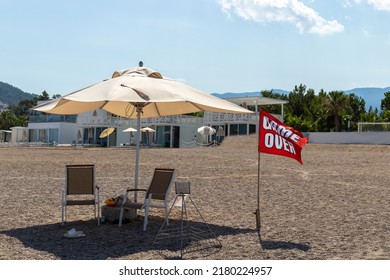 There is an umbrella on the beach and the flag next to it says game over.