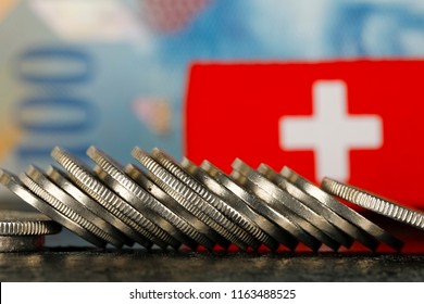 There are various Swiss coins visible against background of one hundred francs banknote and there is Swiss flag as well - Shutterstock ID 1163488525