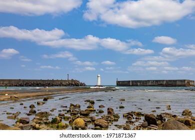 There Is A White Lighthouse In The Middle Of The Long Causeway On The Beach