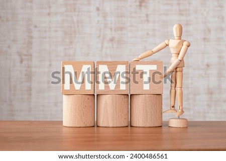 There is wood cube with the word MMT. It is as an eye-catching image.
