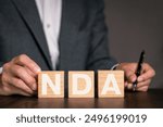 There is wood cube with the word NDA. It is an abbreviation for Mutual Non-Disclosure Agreement as eye-catching image.