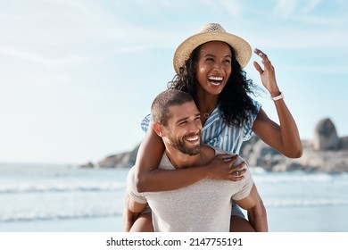 Theres always love in the air. Shot of a young man piggybacking his girlfriend at the beach. - Powered by Shutterstock