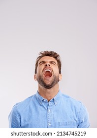 Theres No Hiding His Feelings. Studio Shot Of A Handsome Young Man Screaming In Anger Against A Gray Background.