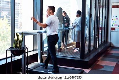 Theres no need to be deskbound as you head to success. Shot of a young businessman talking on a cellphone and going through paperwork while walking on a treadmill in an office. - Powered by Shutterstock