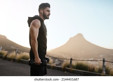 Theres No Time To Waste Time With Excuses. Shot Of A Sporty Young Man Exercising With Weights Outdoors.