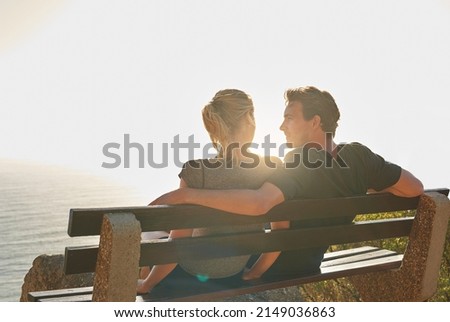 Theres nothing more romantic than watching the sunset. Shot of a loving couple sitting on a bench overlooking the ocean.