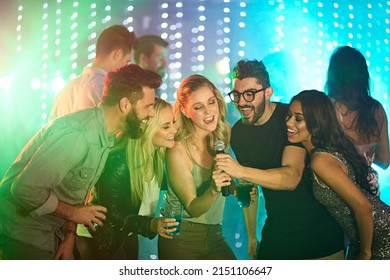 Theres a superstar in all of us. Shot of a group of friends singing karaoke at a party.