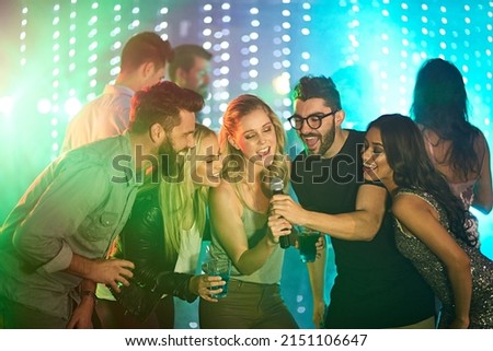 Theres a superstar in all of us. Shot of a group of friends singing karaoke at a party.