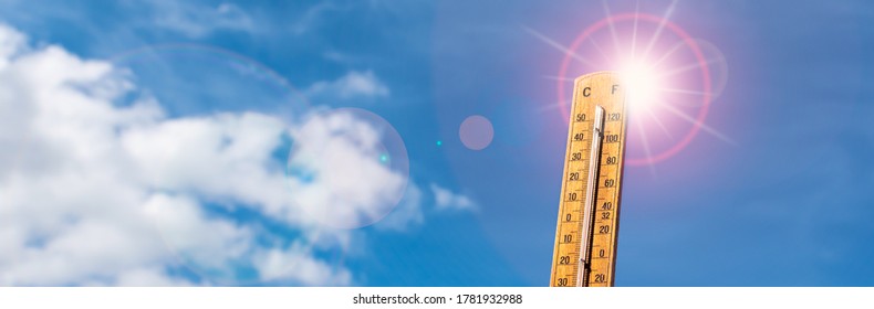 Thermometer against blue sunny sky. Hot summer weather concept.