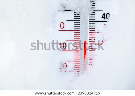 Thermometer with both Celsius and Fahrenheit scales placed in fresh snow indicating cold winter temperature