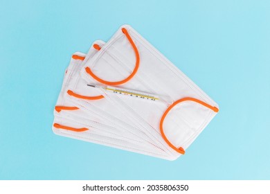 Thermometer And Disposable Medical Masks Isolated On Blue Background, Personal Health Monitoring And Protection Concept