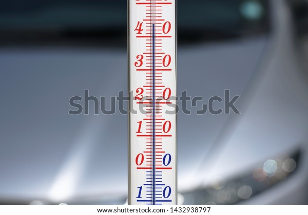 Thermometer\
during hot weather with car in\
background