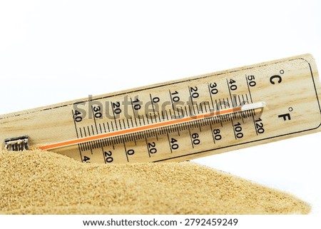 Thermometer indicating extremely high temperature, partially submerged in sand. Representing global warming, hot weather, and heatwaves
