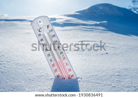The thermometer lies on the snow in winter showing a negative temperature.Meteorological conditions in a harsh climate in winter with low air and ambient temperatures.Freeze in wintertime.Sunny winter
