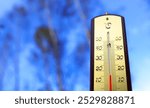 Thermometer for measuring outdoor air temperature. Cold weather in autumn season. Meteorological device for observing, measuring the weather. Weather forecast. Thermometer on blue sky background. 