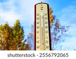 Thermometer for measuring outdoor air temperature. Cold weather in winter season. Meteorological device for observing, measuring the weather. Weather forecast. Thermometer on autumn background. 