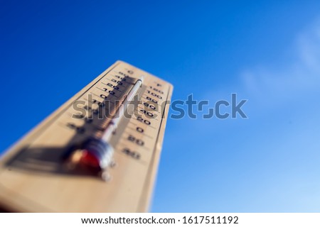 Thermometer on the blue sky background. Weather forecast and outdoor temperature concept