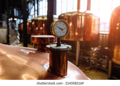 Thermometer or pressure gauge on copper colored brewery tanks close up.