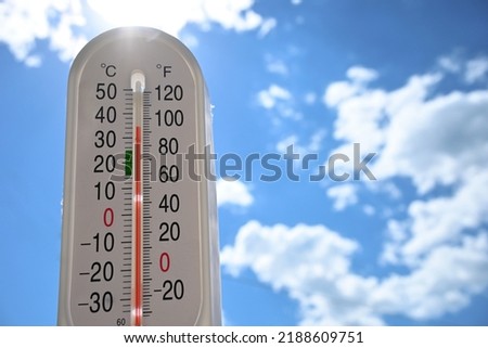 thermometer showing high temperature against a sunny sky, concept for hot weather