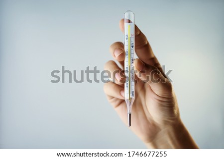Thermometer in a woman's hand isolated on a clean background. Temperature measuring. Fever measuring.