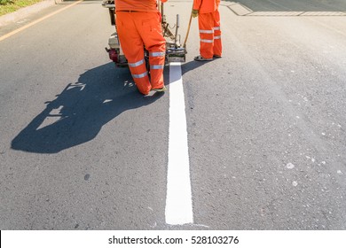 Thermoplastic spray marking machine during road construction.
Worker painting white line on the street surface (Road worker painting)

