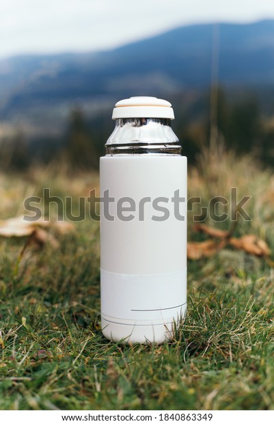 Thermos bottle on mountain nature background.\
Coffee or tea reusable bottle container. Thermo cup travel tumbler.\
Insulated drink\
container.