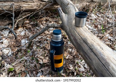 Thermos Cup With Tea On A Tree Trunk In The Forest, Concept Of Tourism And Hiking, Selective Focus, Tinted Image