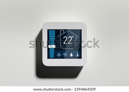 Thermostat displaying temperature in Celsius scale and different icons. Smart home device on white wall