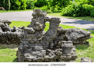 These ancient, eroded geological structures are a striking natural sculpture in a serene outdoor setting with lush greenery and a paved path