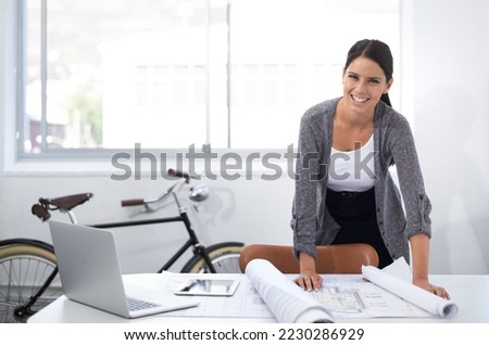 These plans are coming along nicely. Smiling young designer standing at her desk.