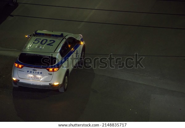 Thessaloniki, Greece - April 22 2022: Elevated\
view of Greek police car with alarm lights on blocking the street\
during a night\
event.