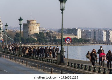 Thessaloniki, Greece - February 27 2021: People With Covid-19 Masks Before The City Landmark. Large Crowd With Face Protection Walks At The Waterfront Area Of The White Tower.