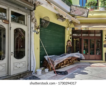 Thessaloniki, Greece - May 11 2020: Empty Outdoors Tables Stacked Outside. Day View Of Wooden Tavern Furniture Next To Closed Restaurants At A Pedestrian Area In The City Center.