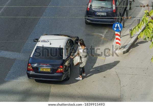 Thessaloniki, Greece - October 24 2010:\
Woman with covid-19 mask ready to go in a taxi. An unidentified\
female with face protection entering a cab on a public\
street.