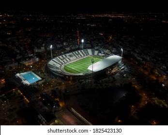 Thessaloniki, Greece - September 30 2020: landscape drone shot of PAOK FC Toumba stadium with grass. Aerial top night view of football court with pitch & team name written on the stands, without fans.