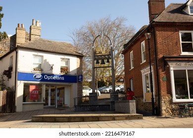 THETFORD, UNITED KINGDOM - Apr 01, 2022: A Man At Bells Monument With Boots Optician And Tall Orders Cafe Around In King Street, Thetford, UK