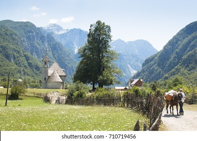 THETH, ALBANIA - AUGUST 2017: Mountain Landscape With Church And Farmer With Horse In Theth In The Albanian Alps