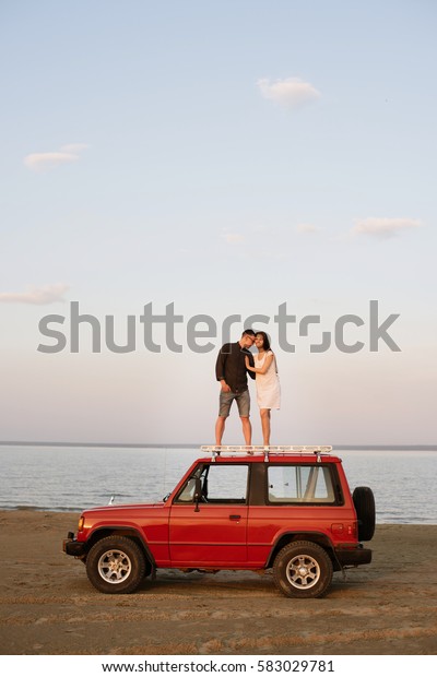  They found the perfect spot for some loving. Cropped \
shot of couple watching together sunrise on the roof of their car.\
