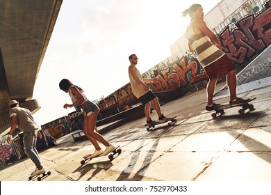 They Know How To Skate. Full Length Of Young People Skateboarding While Hanging Out At The Skate Park Outdoors