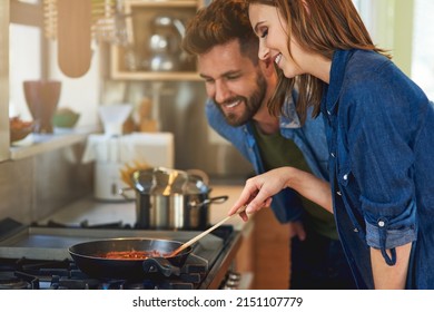They like their meals home cooked and hearty. Shot of a happy young couple cooking a meal together on the stove at home.